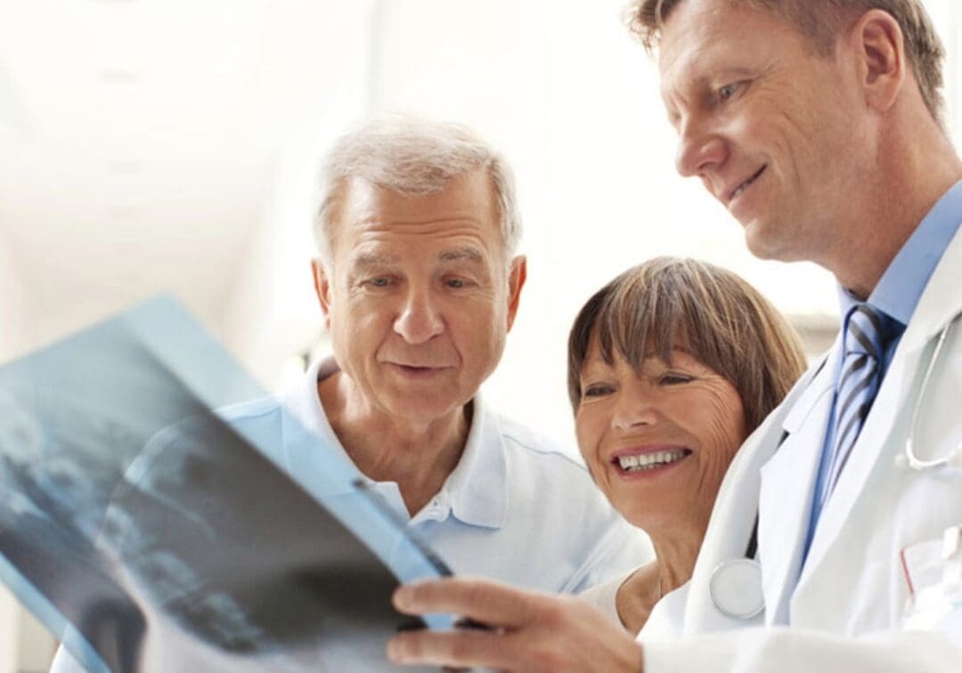 Close up of a doctor standing with two elderly patients in a hospital corridor discussing a patient's diagnosis