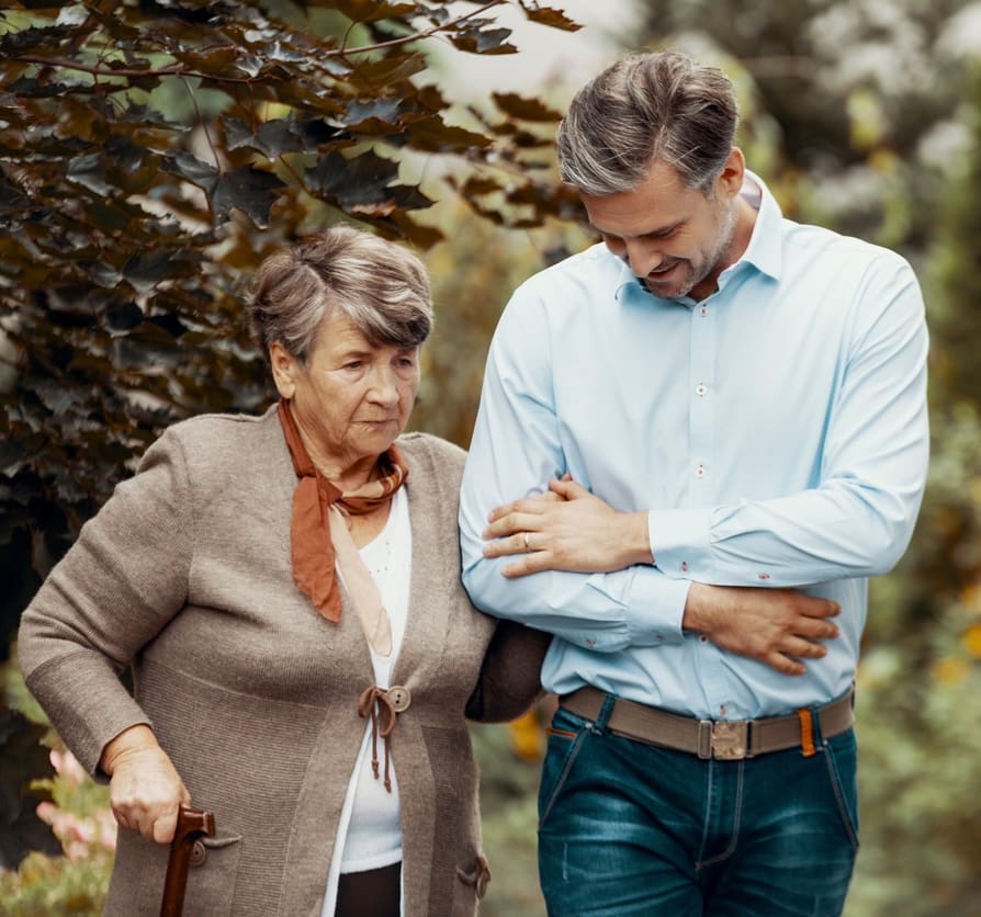 Worried grey senior lady with walking cane in the garden with her son Worried grey senior lady with walking cane in the garden with her son